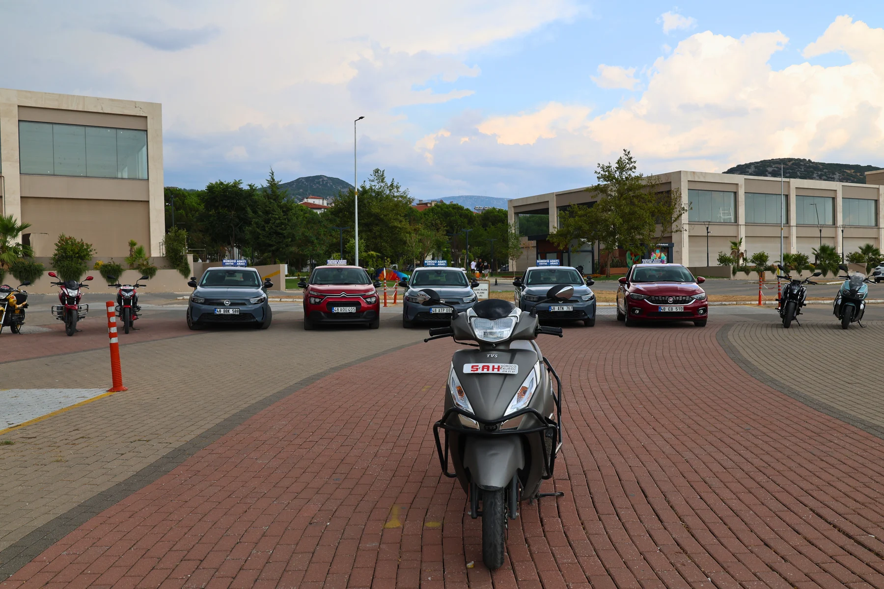A Şah Driving School scooter with other training vehicles behind it